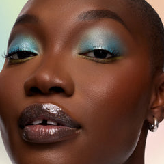 Model with deep skin wearing Vaporeon aqua Multichrome Shadow Stix on the lids