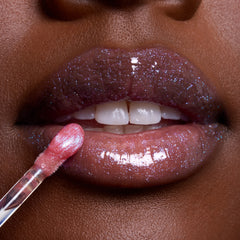 Close-up glossy lips wearing Courageous Rapunzel Ultra Glossy Lip, a shimmery purple-pink Disney Princess lip gloss, as a wand applicator glides on sparkling color for a high-shine finish.