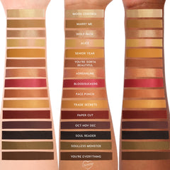 ColourPop New Moon Shadow Palette swatches stripe three skin tones, showing warm golds, coppers, reds, browns, black and olive in matte and shimmer finishes, with shade names like Mood Control, Marry Me, Adrenaline, Bloodsuckers, and Youβre Everything.