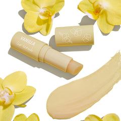 ColourPop Vanilla Lip Scrub stick uncapped to reveal balm, with a creamy vanilla-beige swatch, the cap printed with orchid line art, surrounded by yellow orchid flowers on a clean white background.