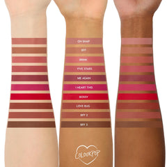 Three arms in light, medium, and deep skin tones display swatches of The Lil Box of Lippie Pencils lip liner shades from Colourpop, arranged in horizontal strips labeled from nude mauves to bright reds and warm browns for comparison.
