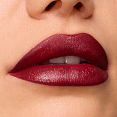 Slow Burn ColourPop Lux Lipstick draping full lips in a deep wine‑burgundy satin finish, showing smooth, precise edges and creamy payoff in a tight macro beauty close‑up.