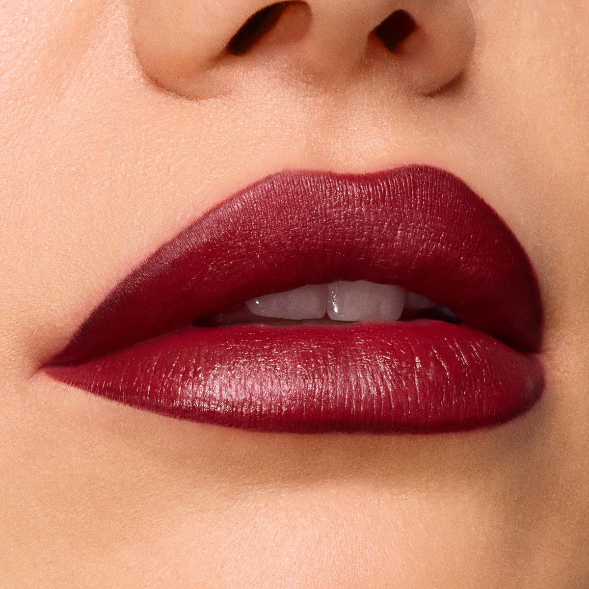 Slow Burn ColourPop Lux Lipstick draping full lips in a deep wine‑burgundy satin finish, showing smooth, precise edges and creamy payoff in a tight macro beauty close‑up.