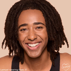 Smiling model wears Dark 17, showcasing smooth, natural coverage and a dewy finish from the ColourPop Pretty Fresh Tinted Foundation Balm, close-up against a beige background to highlight shade match and lightweight balm foundation results.