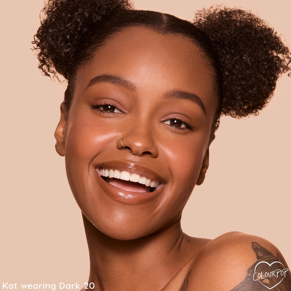 Smiling model wearing ColourPop Pretty Fresh Tinted Foundation Balm shade Dark 20, showcasing an even, dewy finish; close-up face with glossy lips and natural brows against a soft beige studio background.