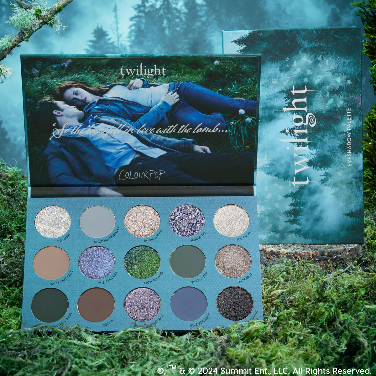 ColourPop Twilight Shadow Palette opened to reveal 15 coolβtoned matte and shimmer eyeshadows in gray, blue, green, and taupe, set on moss with the outer box; inner lid shows two characters on grass, echoing a misty forest aesthetic. ColourPop Shadow Palette.