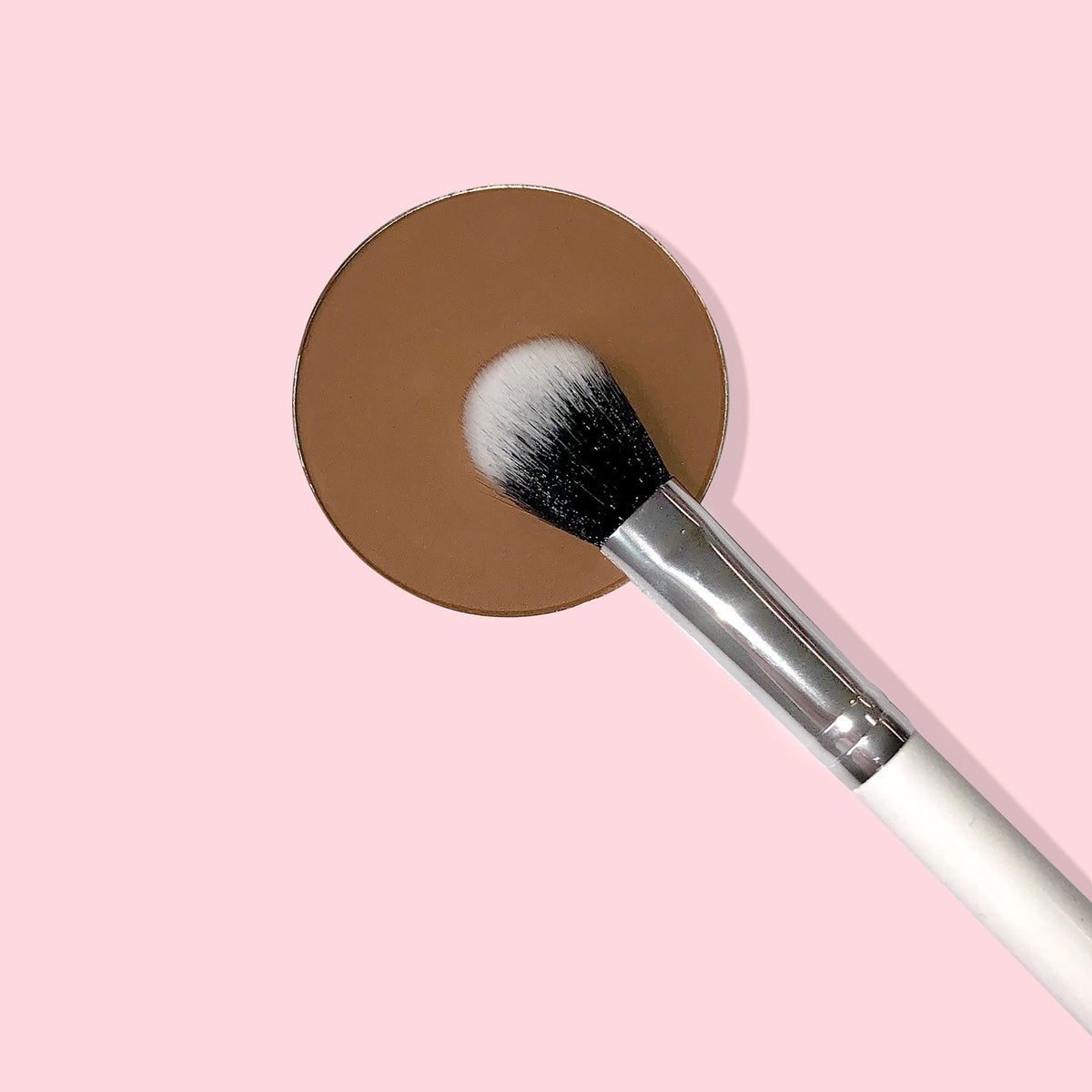 Small Fluff Brush makeup brush blending a brown round eyeshadow pan; dual‑tone black‑to‑white bristles, silver ferrule, and white handle on a pastel pink background, ideal for soft crease blending with ColourPop eyeshadows.