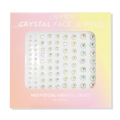 ColourPop Crystal Face Jewels Individual sheet displaying 81 iridescent round adhesive crystals in varied sizes arranged in neat rows, set in pastel pink-to-yellow ombré packaging for customizable face accents.