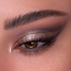 Shimmery taupe and metallic champagne eyeshadow with soft charcoal smoke on the outer crease, shown on a close-up eye with defined lashes and brow, created using ColourPop Of Quartz Shadow Palette for a cool-toned glam look.