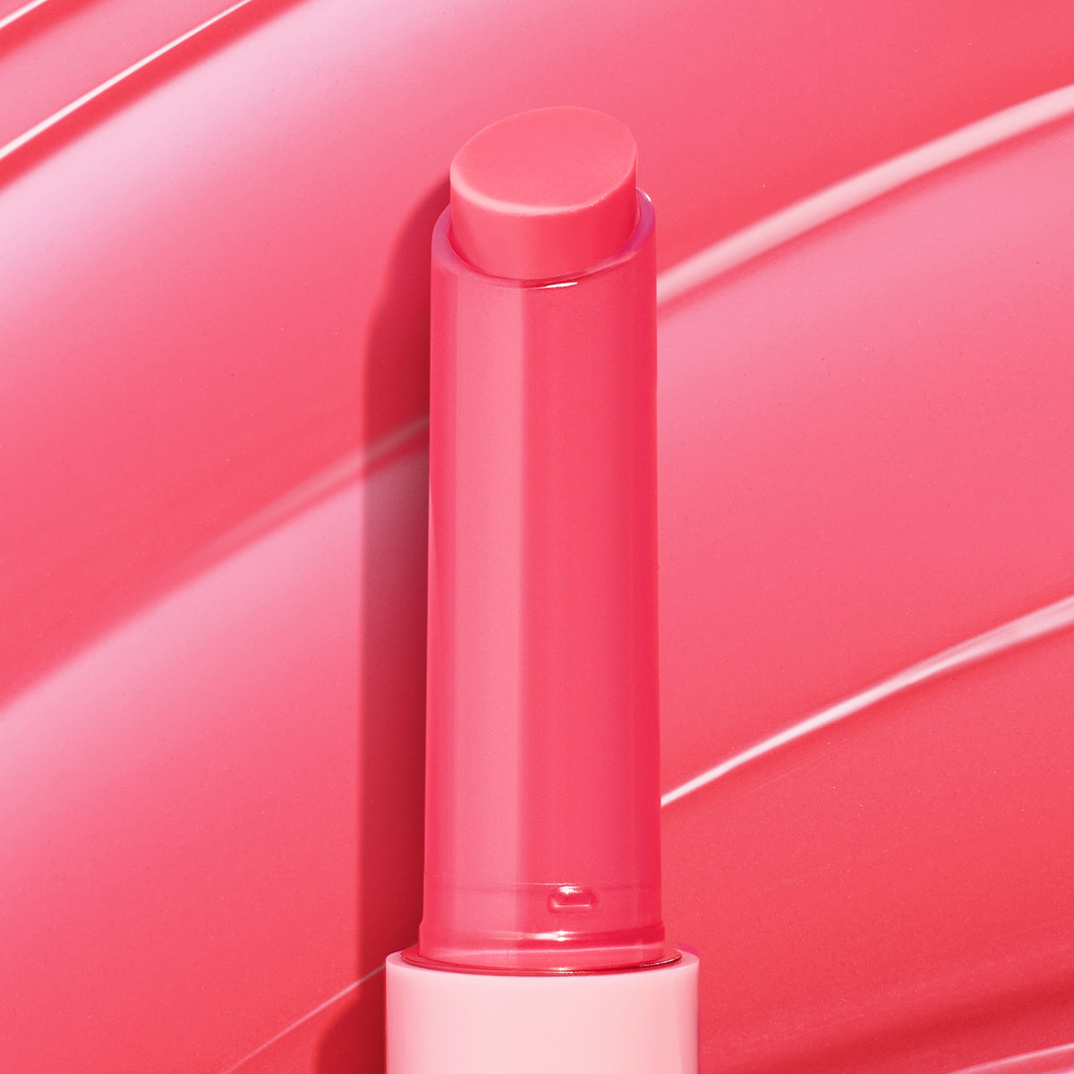 Passenger Princess, a bright pink twist-up stick of ColourPop So Juicy Plumping Gloss Balm with Peptides, shown fully extended with a dewy sheen against a matching glossy swatch background highlighting its shiny, cushiony finish.