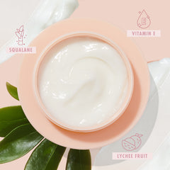 Peach jar of The Daily Face Cream opens to a glossy swirl, a hydrating ColourPop Face Moisturizer, set on a pale pink background with green leaves, cream smears, and ingredient icons for squalane, vitamin E, and lychee fruit.