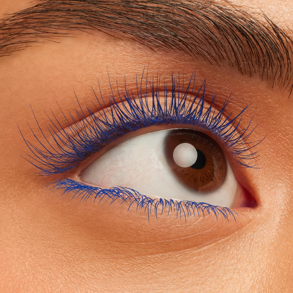 Fanned-out lashes coated in Blue Ya Mind BFF Mascara, showcasing bold electric-blue pigment and length on a close-up brown eye; studio swatch of ColourPop BFF Mascara on upper and lower lashes.