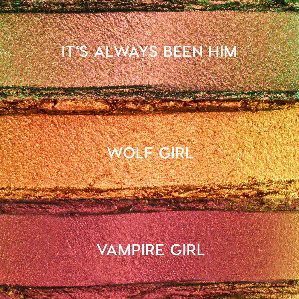 ColourPop Shadow Stix Love Triangle bundle swatches showing three metallic shades - It’s Always Been Him (pink‑green duochrome), Wolf Girl (copper gold), and Vampire Girl (rosy plum) - spread in horizontal strips on a textured makeup surface.
