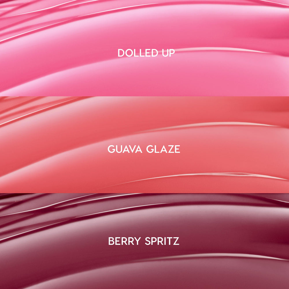 ColourPop So Juicy Plumping Gloss Balm with Peptides swatches showing She’s So Juicy shades: Dolled Up (bright pink), Guava Glaze (coral peach), and Berry Spritz (deep berry), displayed as glossy curved stripes in a close-up bundle layout.