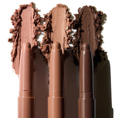 Three ColourPop Shadow Stix in Matte Nudes swipe creamy pigment, leaving wide matte swatches in light taupe, warm caramel, and deep cocoa on a white backdrop, with each twist-up eyeshadow stick aligned beneath its shade.
