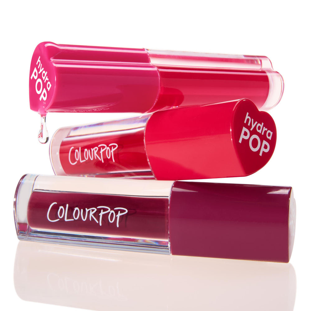 ColourPop Lip Stain Very Berry - three hydra POP lip stain tubes stacked, one with a glossy drip - show bright pink and deep berry shades in clear barrels on a white reflective studio background.