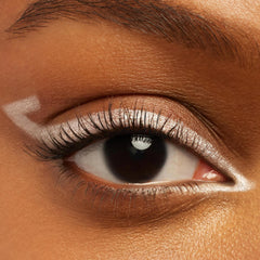 Eye wearing ColourPop Crème Gel Liner Calabasas, a pearly white shade, sweeping along the upper lash line with sharp inner and outer corner points; close-up highlights creamy, precise payoff and defined lashes on warm brown skin.