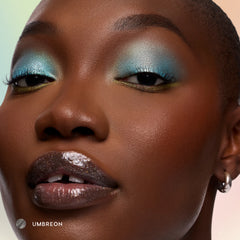 Model with deep skin wearing Umbreon sheer black glossy lip balm with icy blue eyeshadow