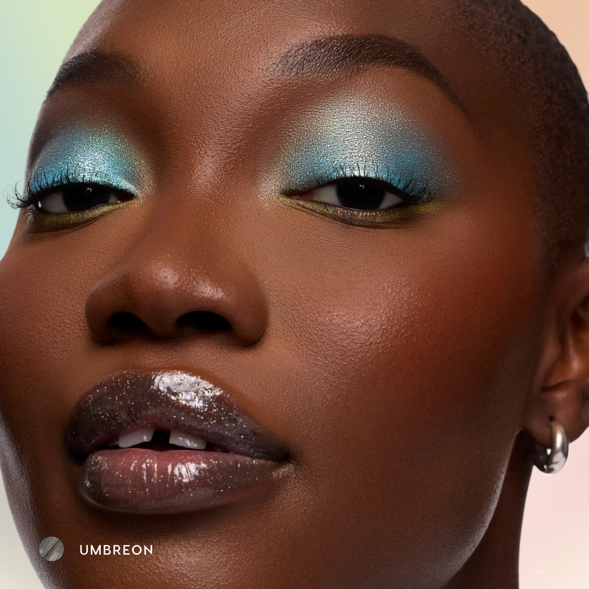 Model with deep skin wearing Umbreon sheer black glossy lip balm with icy blue eyeshadow