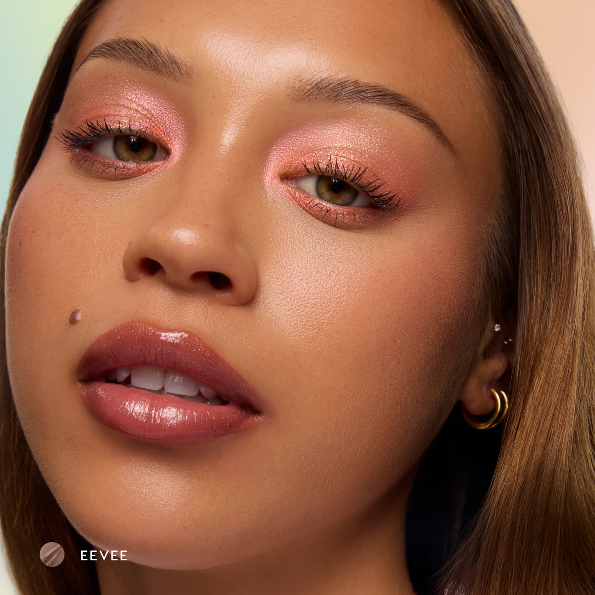 Model with medium skin wearing Eevee sheer nude glossy lip balm with pink eyeshadow