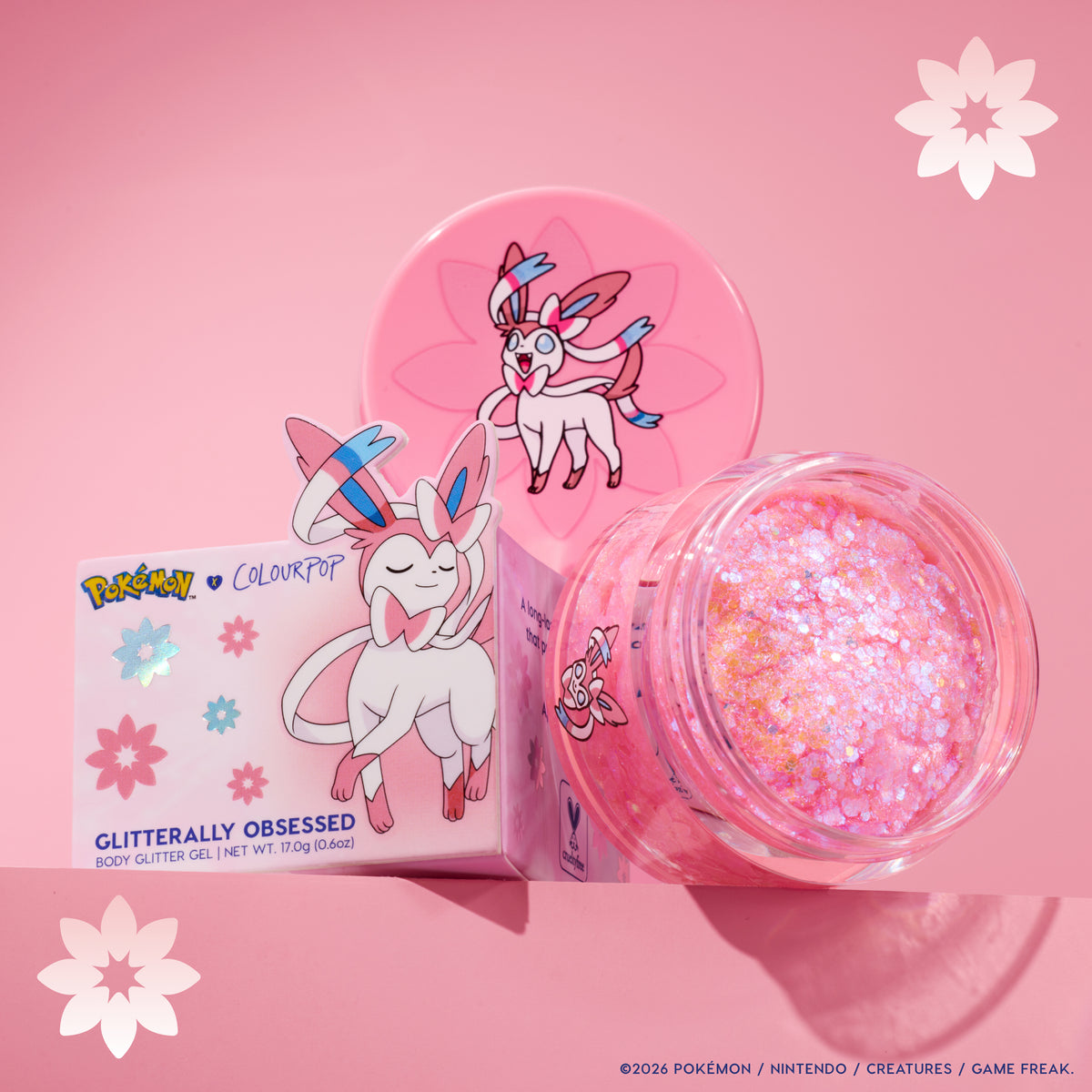 Sylveon Glitterally Obsessed glitter gel jar open beside its Sylveon box on a pink backdrop