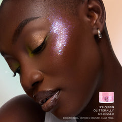 Model with deep skin wearing Sylveon Glitterally Obsessed glitter on her cheekbone with golden bronze shadow