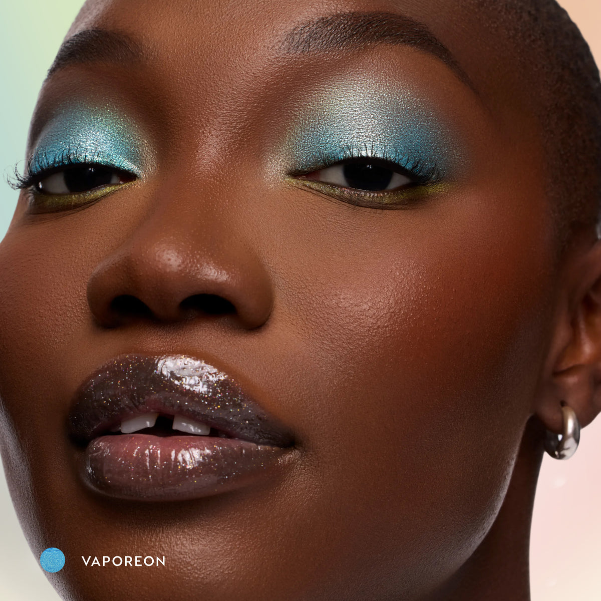 Model with deep skin wearing Vaporeon aqua Multichrome Shadow Stix on the lids