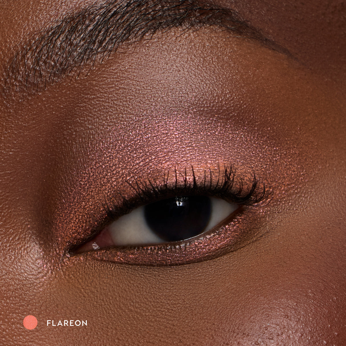 Close-up of a deep-skin eye wearing Flareon tangerine shadow stick