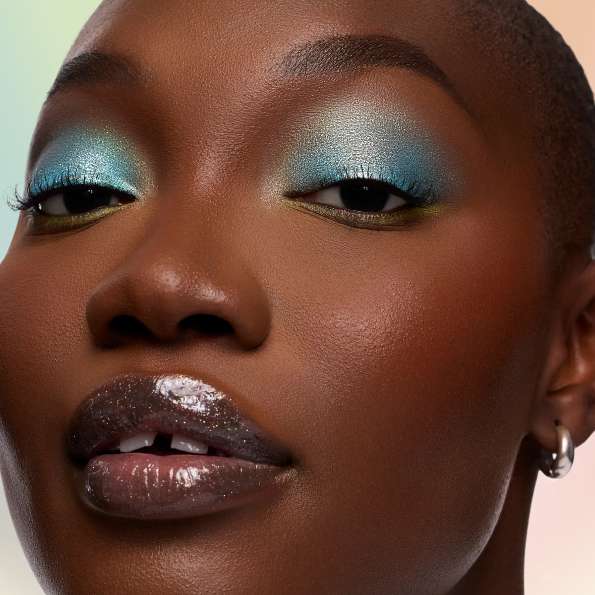 Model with deep skin wearing Vaporeon aqua Multichrome Shadow Stix on the lids