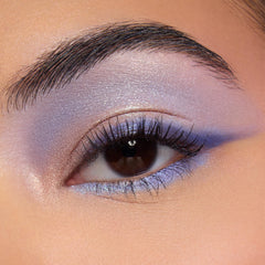 Shimmery lavender and periwinkle eye makeup showcases the Beach Dreamin’ ColourPop Shadow Palette, blending iridescent lilac across the lid with a soft crease fade and lower lash line accent in a studio close-up.