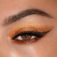 Brown eye wears warm metallic gold and copper eyeshadow with soft winged liner, showcasing Feelin Wild, a ColourPop Shadow Palette Set, in a macro close-up that highlights smooth shimmer and blend on lid and lower lash line.