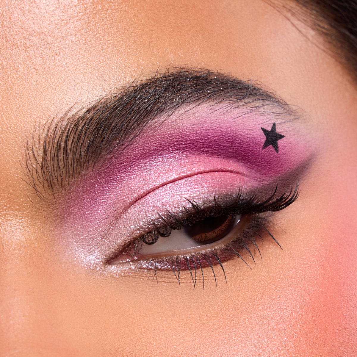 Close-up of a fair-skin eye with pink shadow, black wing and a star stamp above the crease