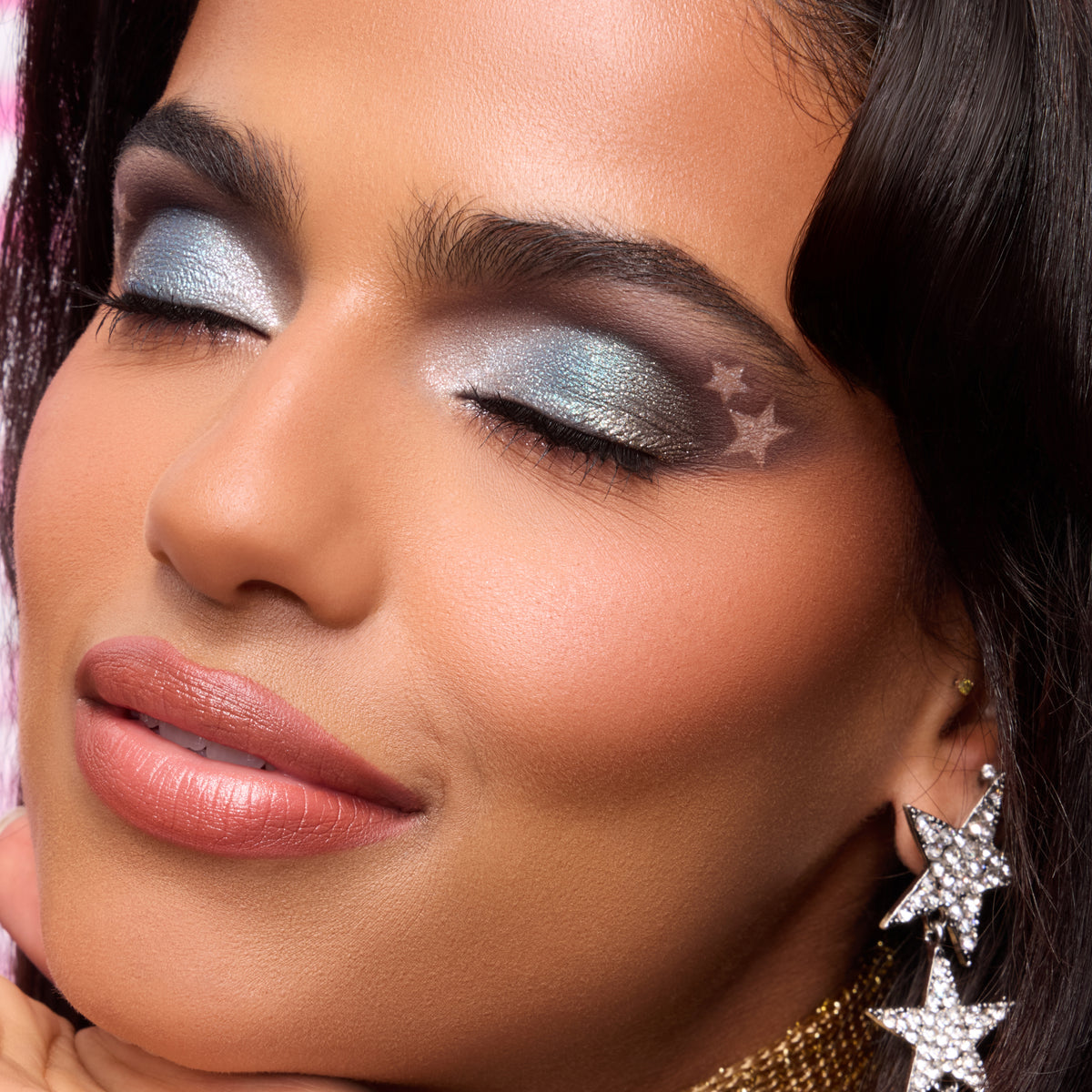 Model with medium skin wearing an icy silver eye with a stamped star from the Hannah Montana collection