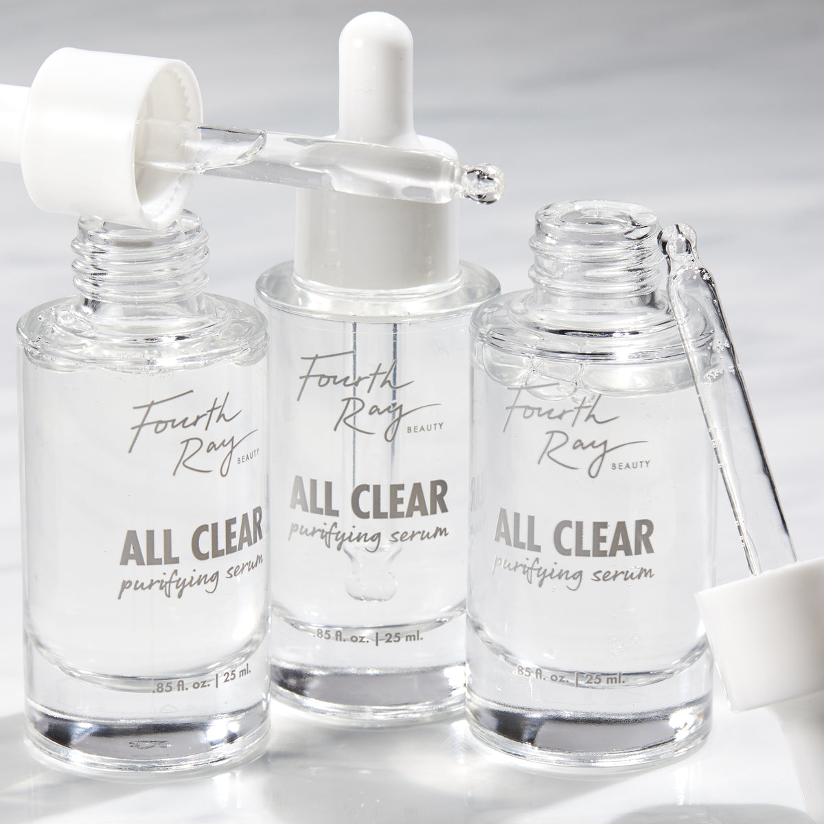 Fourth Ray Beauty All Clear Purifying Serum, a ColourPop Face Serum, three clear 0.85 fl oz (25 mL) glass dropper bottles with pipettes releasing transparent drops on a bright white surface.