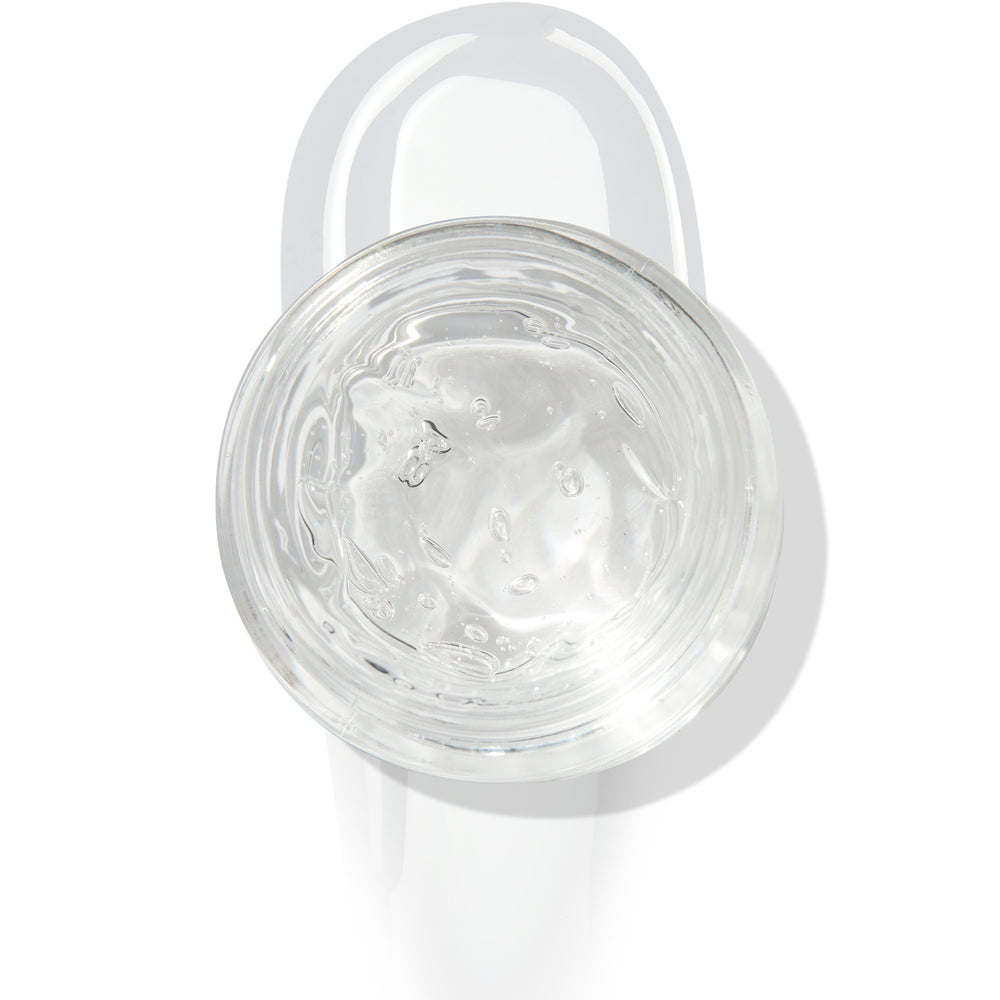 In The Clear Face & Eye Gloss in an open round jar gleams with a glossy swipe beneath it on a white background, showcasing the ColourPop Face & Eye Gloss for dewy, glass-skin shine on lids and cheeks.