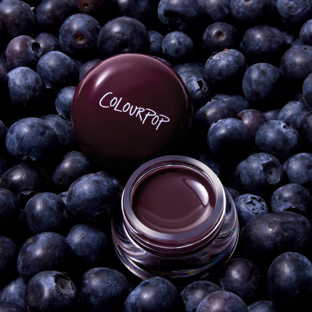 Blueberry Pie Jelly Glow Lip & Cheek Jelly, a deep berry jelly in a clear pot, on a bed of blueberries