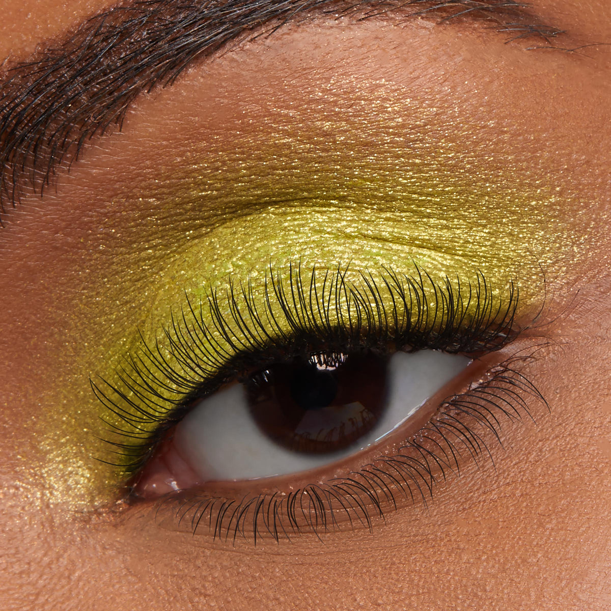 Shimmering chartreuse-gold eyeshadow coats the lid, emphasizing long curled lashes in a macro beauty shot, showcasing ColourPop Jelly Much Shadow in Billionaire - a metallic lime-gold, high-shine jelly formula for bold, long-wear eye looks.