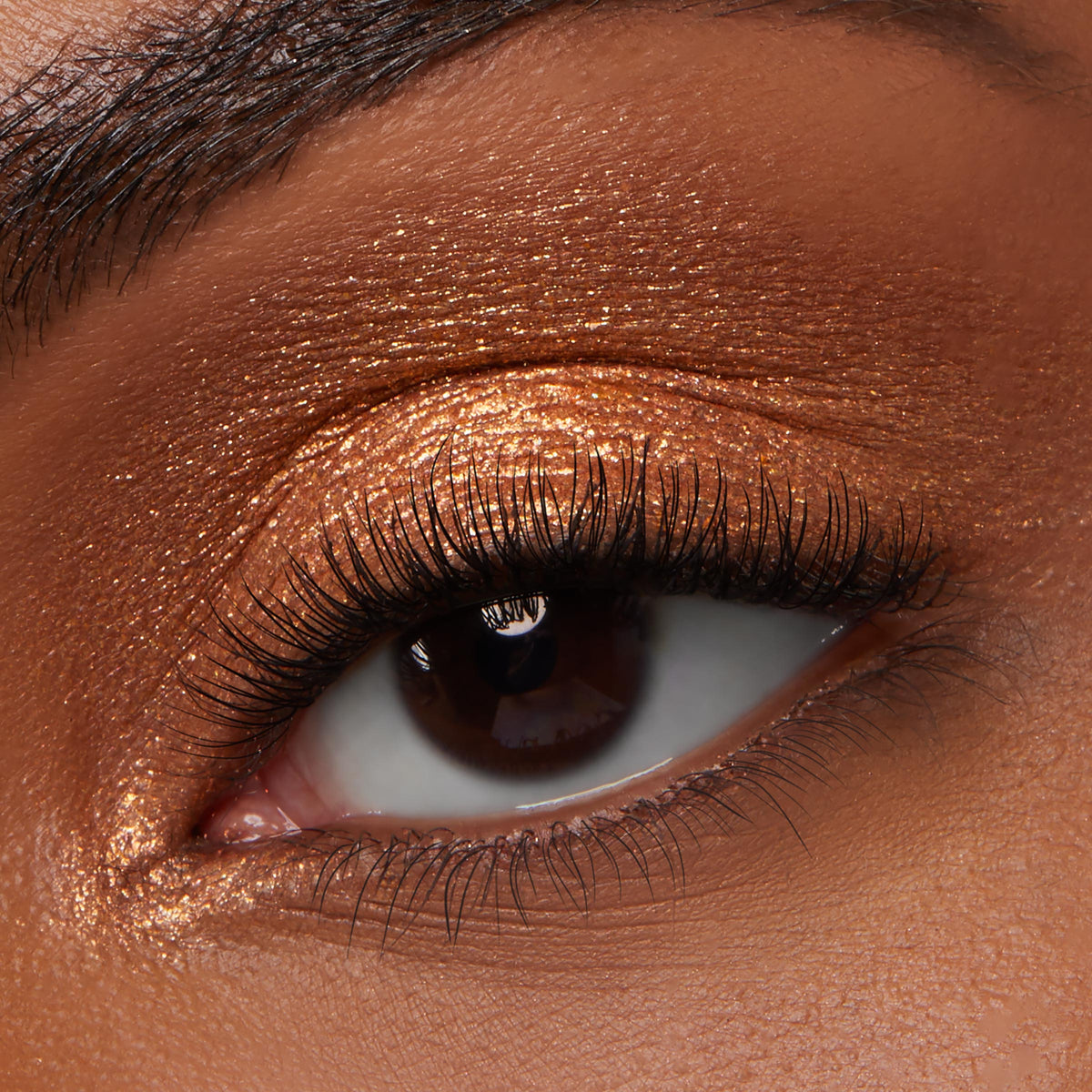Shimmering copper eyeshadow coats an eyelid in a macro beauty shot, showcasing Brentwood from ColourPop Jelly Much Shadow with high-shine metallic payoff and smooth, even coverage, framed by long curled lashes.