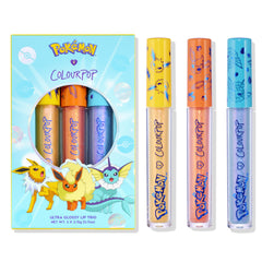 Evolution ColourPop Ultra Glossy Lip trio stands beside its light-blue Pokémon x ColourPop box, decorated with Jolteon, Flareon, and Vaporeon; three shimmery glosses - gold, peach, and icy lavender - sport yellow, orange, and blue character caps.