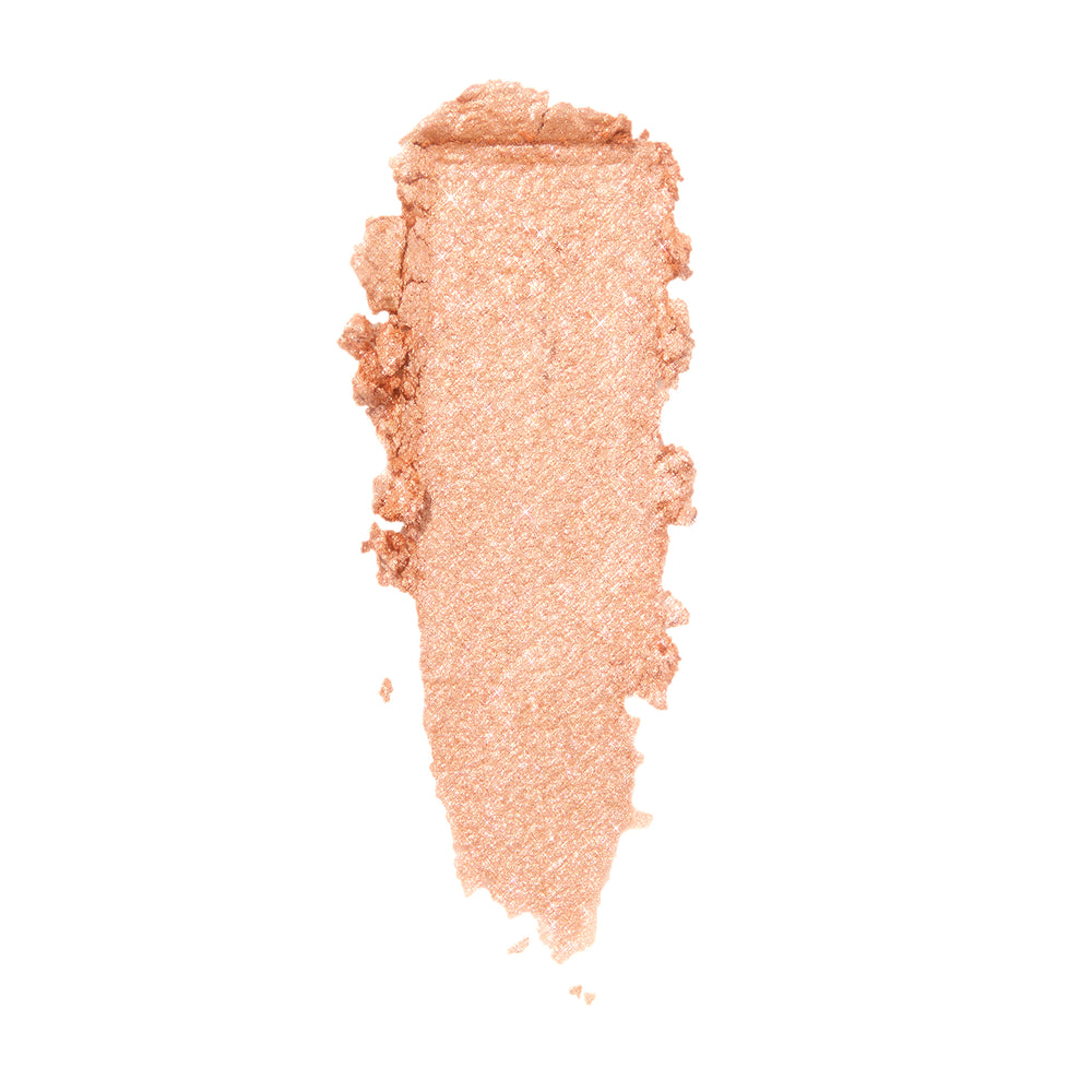 La Mesa ColourPop Super Shock Shadow swatch gliding in a single swipe, a shimmery warm champagne‑peach metallic eyeshadow with fine sparkle, shown as a thick smear on a clean white background.