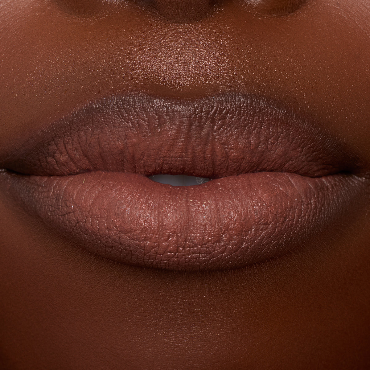 Lips wearing ColourPop Lippie Stix In the Nude, delivering creamy brown‑nude color with smooth, even coverage; macro studio close-up highlights hydrated texture and crisp lip line for an everyday lipstick look.