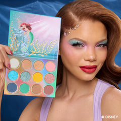 Model with red hair and pearl accents holding the Under the Sea palette, wearing aqua and pink shadow