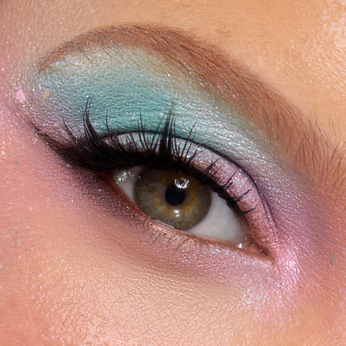 Close-up of a medium-skin eye with seafoam aqua and pink shimmer from the Under the Sea palette