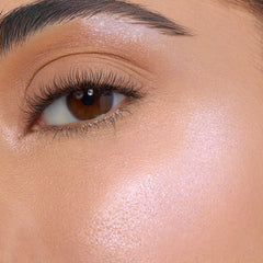 Meadow ColourPop Super Shock Highlighter illuminating the cheekbone and brow bone with a soft pink‑pearl glow in a close-up on-face swatch, showing smooth skin, defined lashes, and a natural, dewy finish.