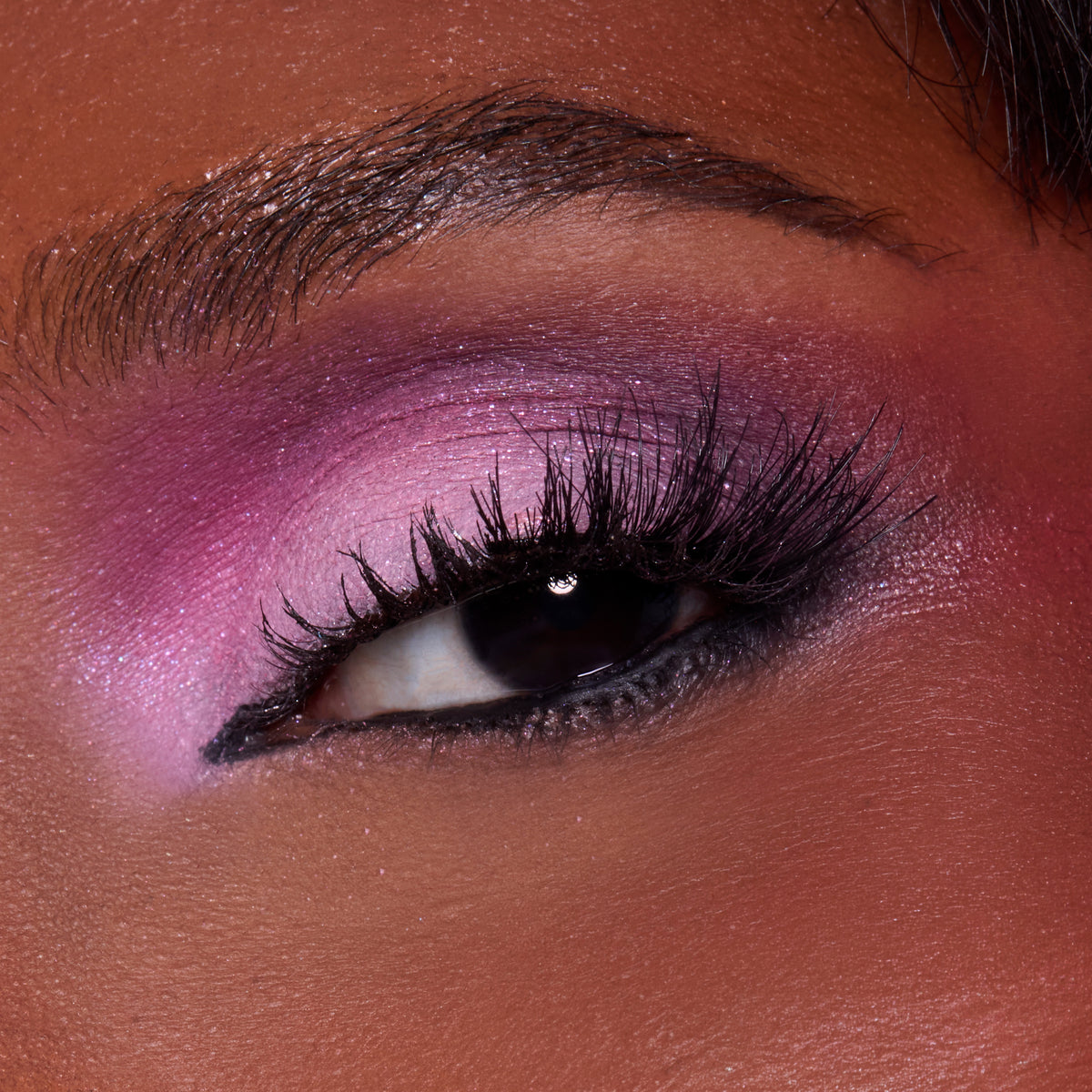Close-up of a deep-skin eye with berry pink shadow and a black wing from the A Very Mickey Christmas palette
