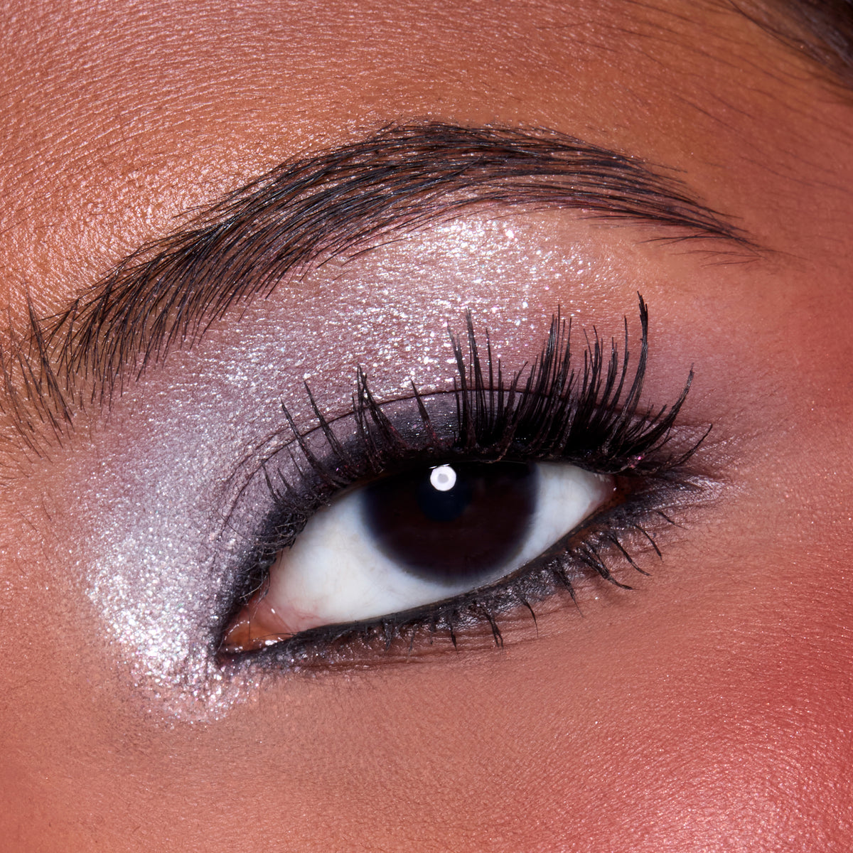 Close-up of a medium-skin eye with sparkling silver shadow and black liner from the A Very Mickey Christmas palette