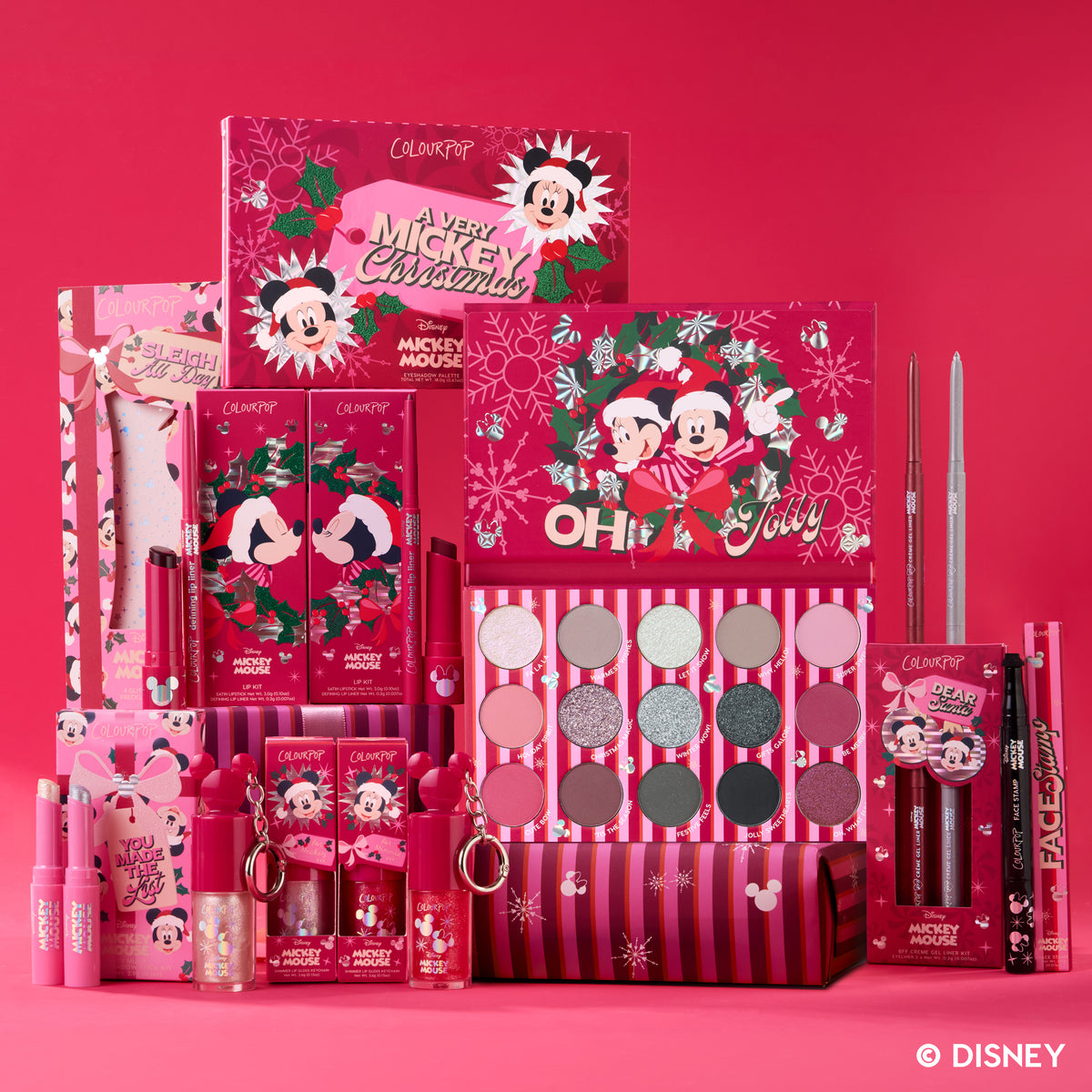 Disney's A Very Mickey Christmas x ColourPop Collection with the palette, lip kits, glosses and face stamp on a red holiday backdrop