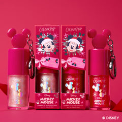 Wrapped with a Bow: two Mickey Mouse-cap Ultra Glossy Lip keychains with their holiday boxes on a red backdrop