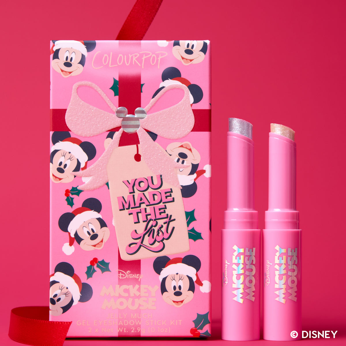 You Made the List kit: two Mickey Mouse Jelly Much Eye Shadow Sticks with their gift-tag box on a red backdrop