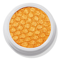 Montecito Super Shock Shadow by ColourPop shimmering in a bold metallic marigold-gold pan, embossed with a honeycomb texture, set in a round white pot against a clean white background.